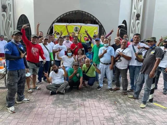 A large group of volunteers and relief recipients gathered in a church courtyard under a yellow MUSA banner.